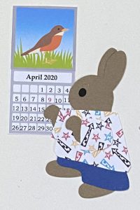 C for calendar, Rabbit standing next to a wall calendar showing the month of April