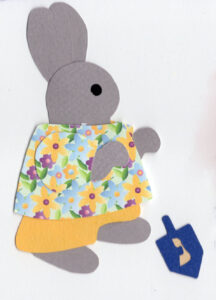 cut paper illustration of an anthropomorphic rabbit playing with a dreidel