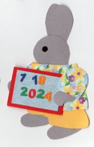cut paper illustration of an anthropomorphic rabbit holding a magnetic slte with colored numbers on it